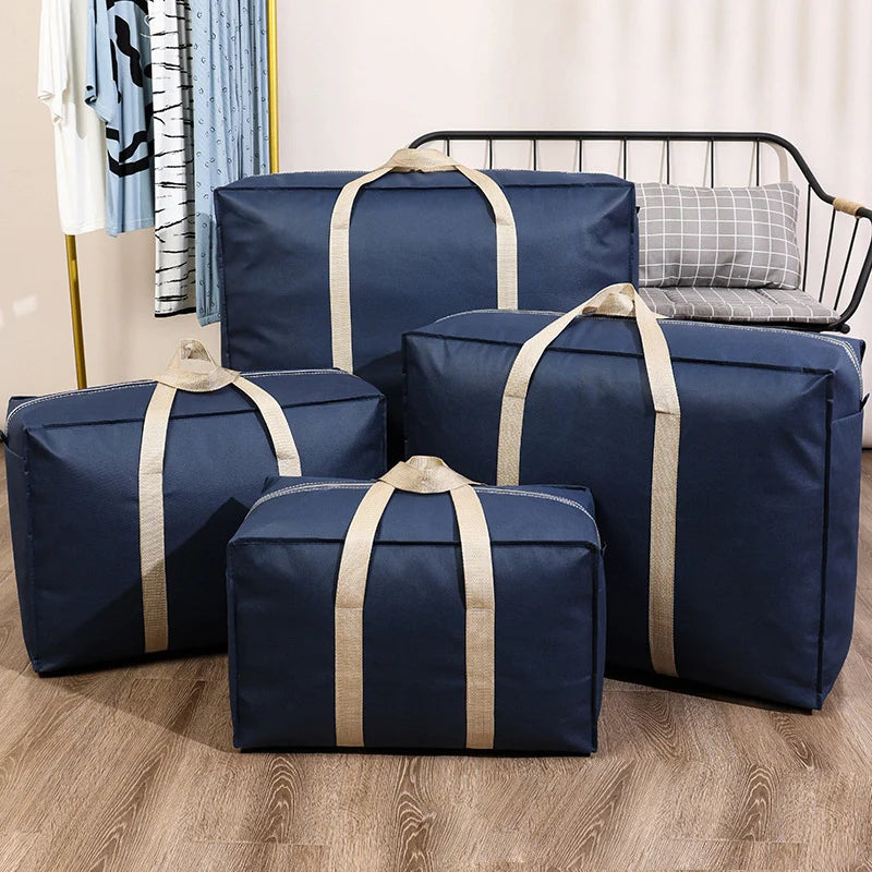 Four navy blue foldable waterproof storage bags with tan straps are displayed on a wooden floor.