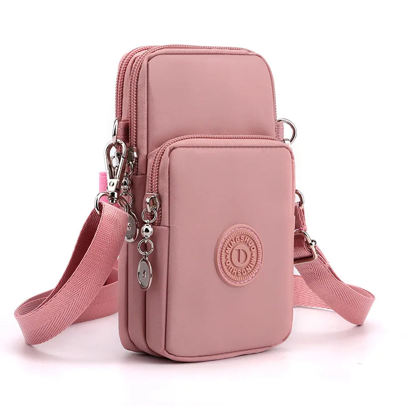 A pink compact nylon crossbody phone bag with a detachable strap and silver hardware.