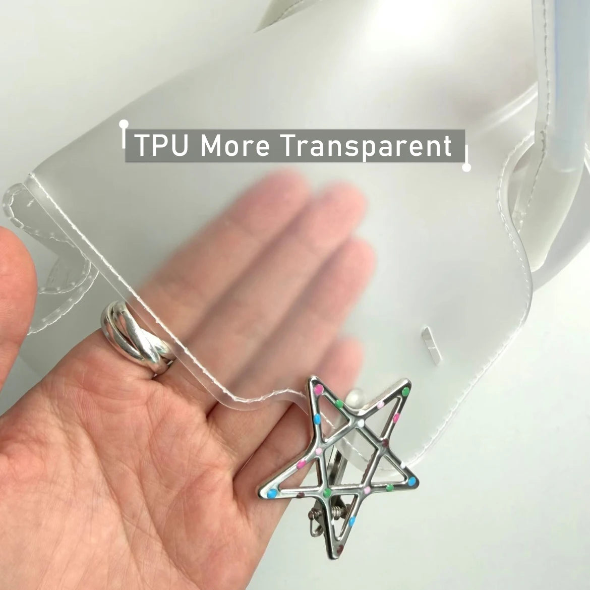 Une main tient un sac en TPU transparent orné d'un charm en forme d'étoile.