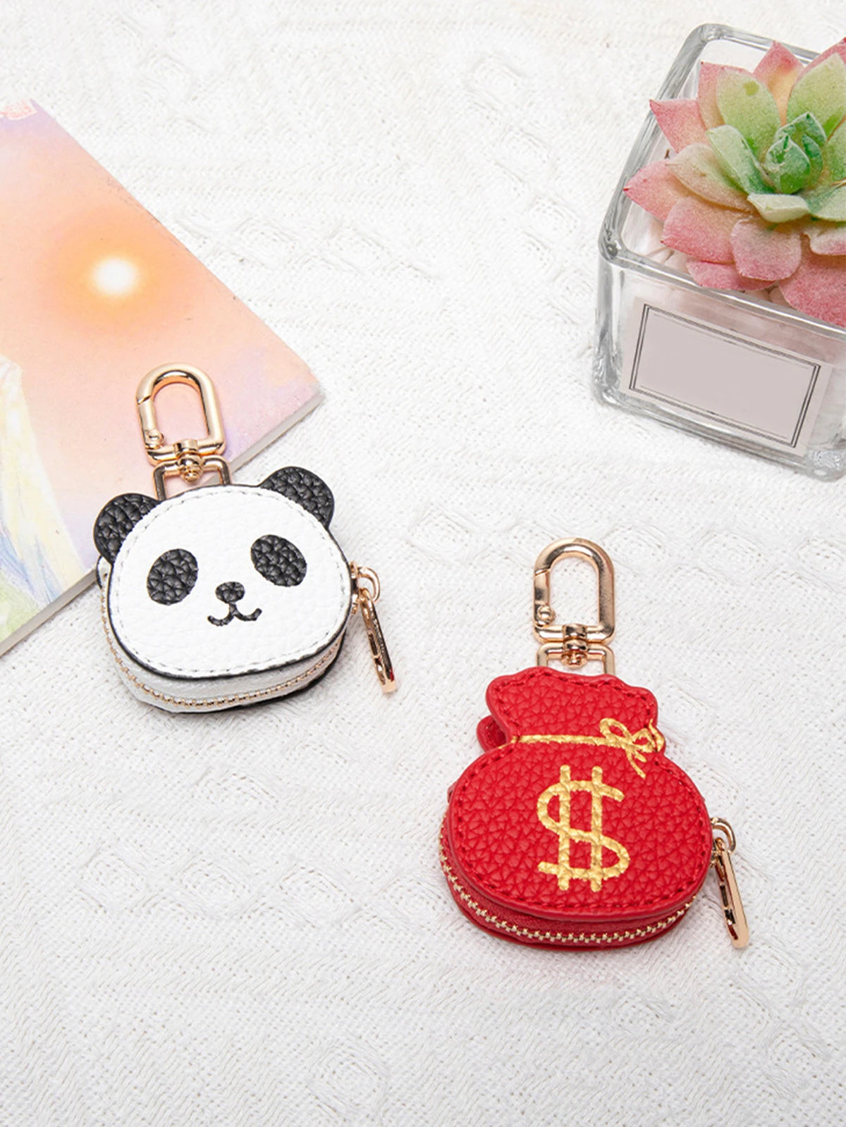 Pequeña cartera de monedas panda blanca con herrajes dorados, sobre tela blanca junto a una suculenta rosa.