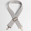 A beige adjustable wide crossbody bag strap featuring a textured maze pattern and gold-toned hardware.