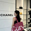 A woman stands in a luxury boutique displaying a pink curved tote bag against a white wall.