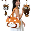 A woman is holding an orange red panda plush backpack and a hanging red panda charm.