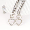 Silver heart-shaped metal purse chain extender with a link chain displayed on a clear acrylic surface.