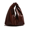 A dark brown leather minimalist crossbody tote bag folded and displayed on a white background.
