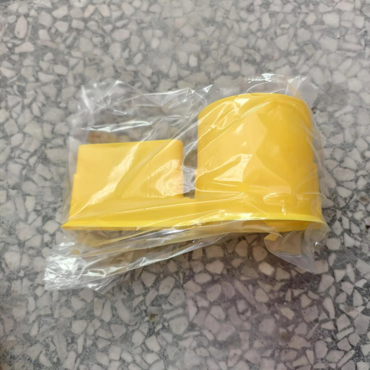 Yellow multi-functional kayak drink holder and phone stand packaged in clear plastic.