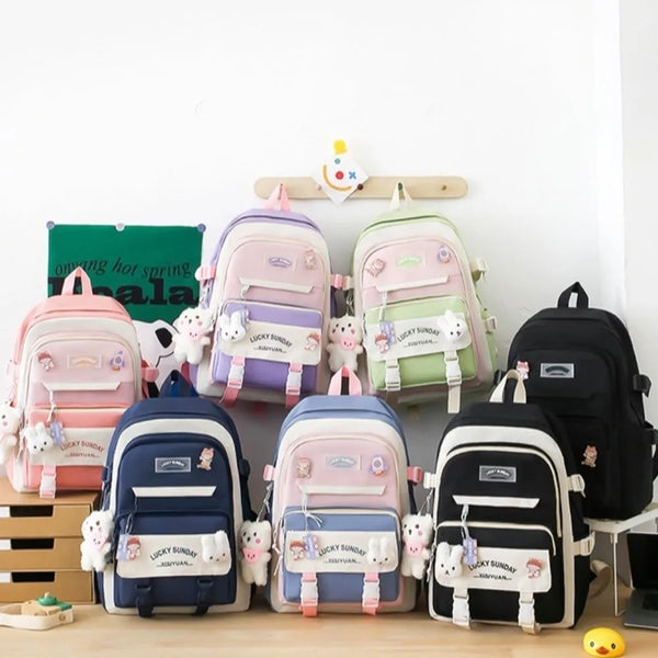 A set of five pink and green nylon backpacks with cartoon designs displayed on a wooden surface.