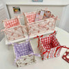 A collection of quilted cotton storage baskets in pink, white, and red patterns with lace flower designs.