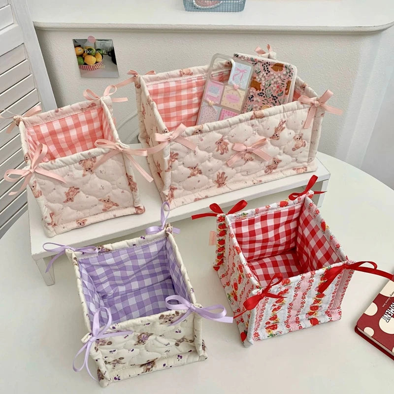 A collection of quilted cotton storage baskets in pink, white, and red patterns with lace flower designs.