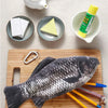 A fun fish-shaped pencil case and coin purse is displayed on a wooden board with various yellow and pink pencils.
