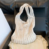A cream-colored bohemian knit shoulder bag displayed inside a black box.