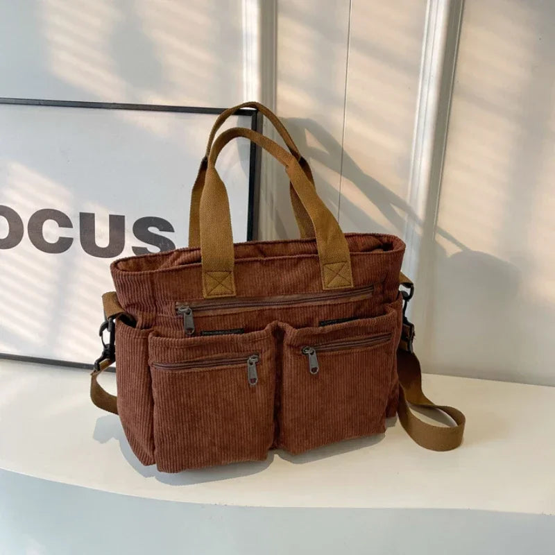 A brown corduroy tote bag with adjustable straps resting on a white surface.