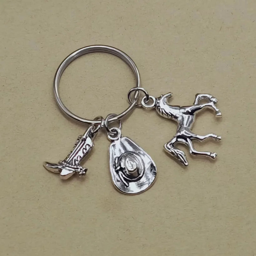 Silver keychain set featuring a cowboy boot, hat, and horseshoe charms.