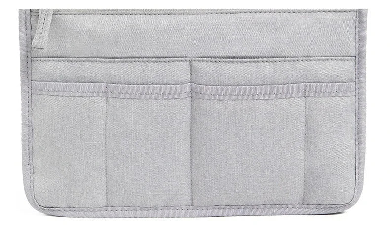 A light gray handbag and purse organizer insert with multiple divided pockets.