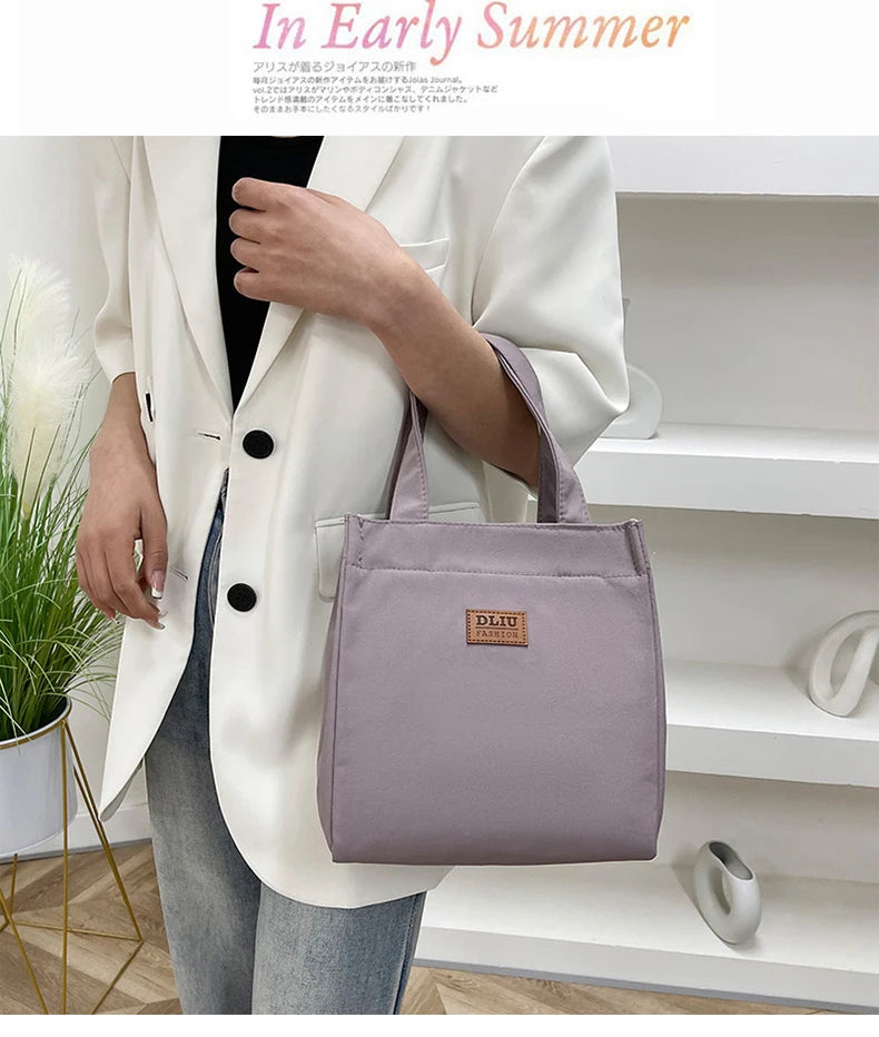 A woman holds a mauve insulated lunch bag in a white blazer, set against a bright indoor background.