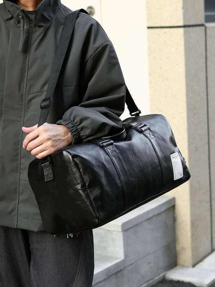 Eine Person hält eine schwarze Kunstleder-Sporttasche vor einem hellen Gebäude.