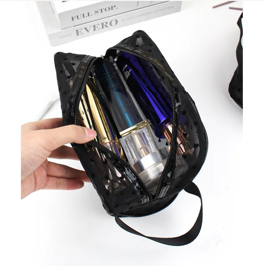 A hand holds a black mesh transparent makeup storage bag filled with various cosmetic bottles.