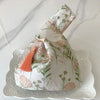 A pale beige silk evening clutch embroidered with floral patterns and featuring a thin orange chain strap.