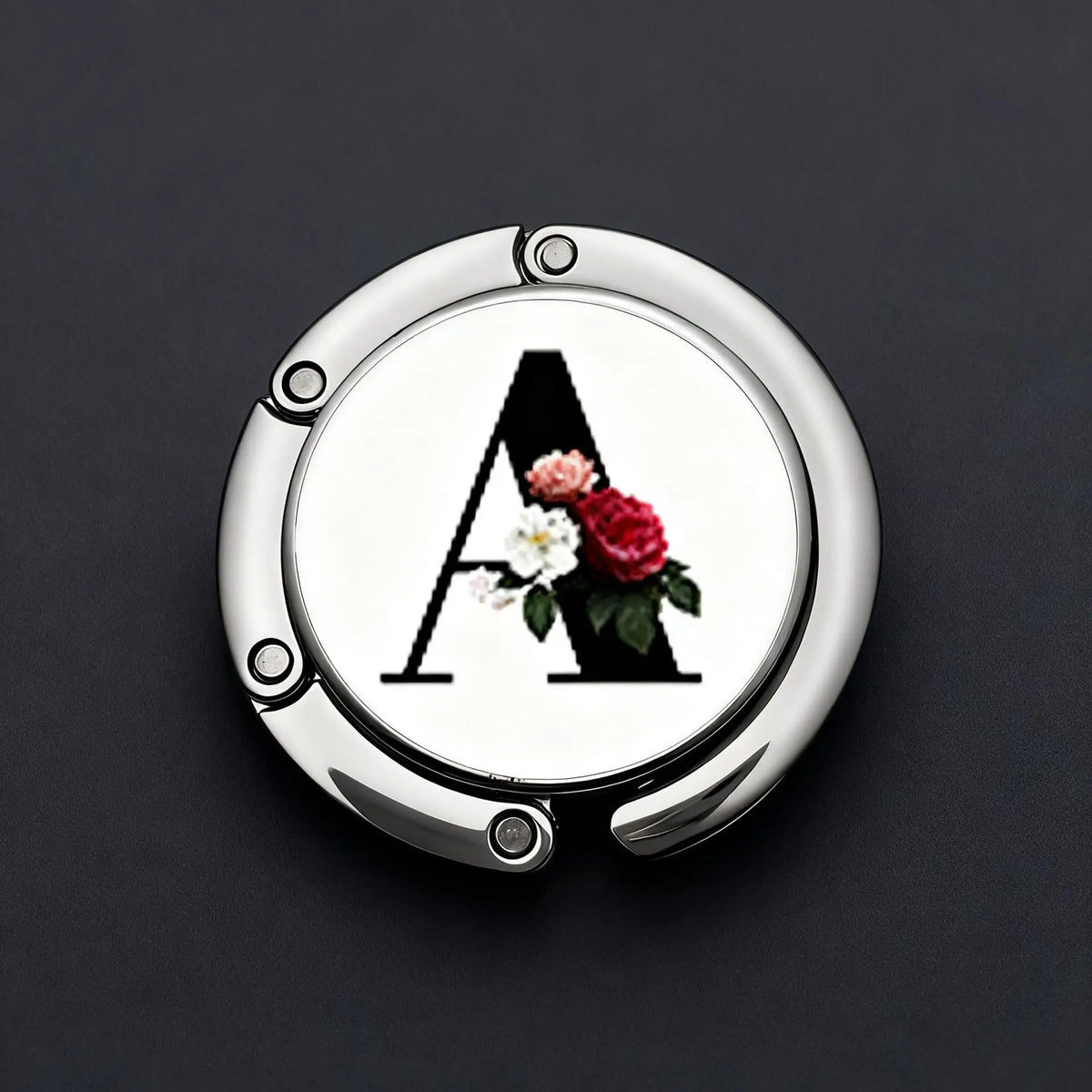 Silver foldable letter hanger hook with an ornate floral design on a dark background