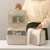 A person holds a beige waterproof makeup organizer and travel pouch with a mesh lining.