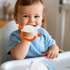 A baby is using a silicone teether shaped like a bunny to suck on it for relief from the urge to nibble.