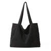 A black canvas shoulder tote bag with long straps shown against a white background.