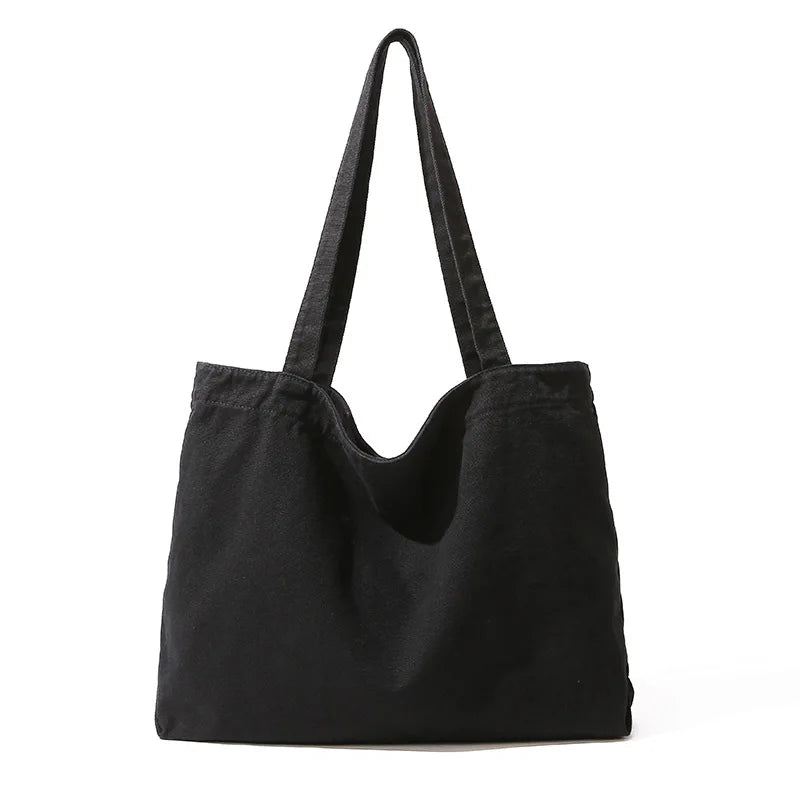 A black canvas shoulder tote bag with long straps shown against a white background.