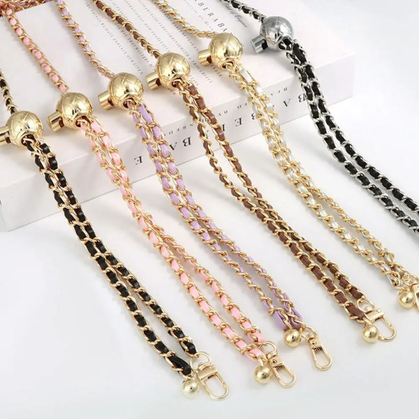 Multiple adjustable metal shoulder straps in gold and black with pink accents displayed on a white background.
