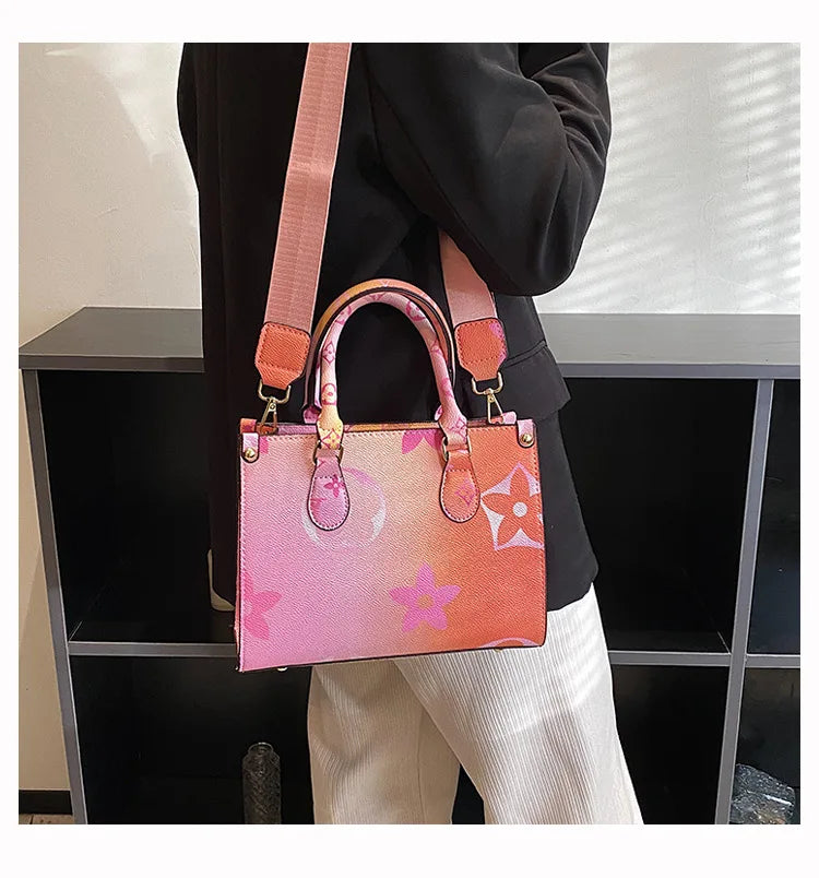 A pink and orange ladies' shoulder tote bag is carried by a person in a black top, resting on a dark shelf.
