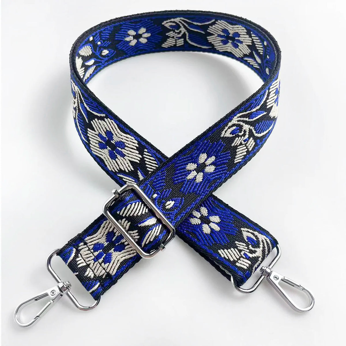A navy blue and white floral patterned fabric strap for a crossbody bag, featuring a silver buckle.