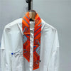 White shirt with an orange and blue patterned silky twill ribbon scarf displayed on a hanger.