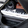 A close-up view inside a black leather backpack showing a camera lens, a smartphone, and some paper.