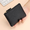 A black genuine leather mini zipper coin and card purse held in a person's hand.