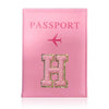 A pink leather passport holder with a gold initial H and a pink airplane design.