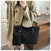 A woman holds a black leopard print tote bag with a leather strap and a matching fabric pouch.