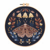 A circular embroidery hoop featuring a detailed butterfly design in shades of brown, gold, and dark blue thread.