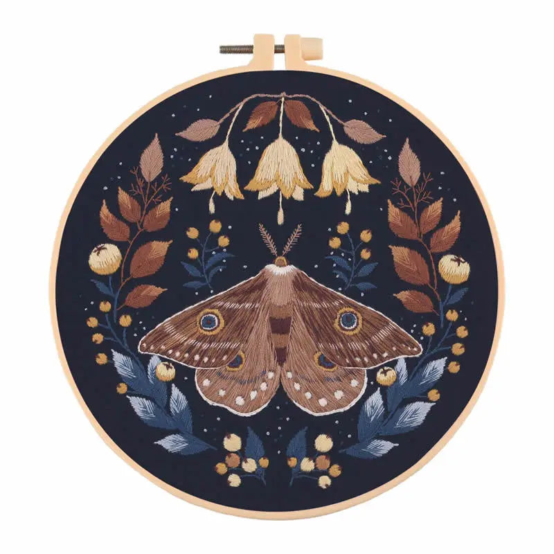 A circular embroidery hoop featuring a detailed butterfly design in shades of brown, gold, and dark blue thread.