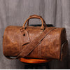 Braune Vintage-Ledertasche mit Ledergriffen auf einer Holzoberfläche.