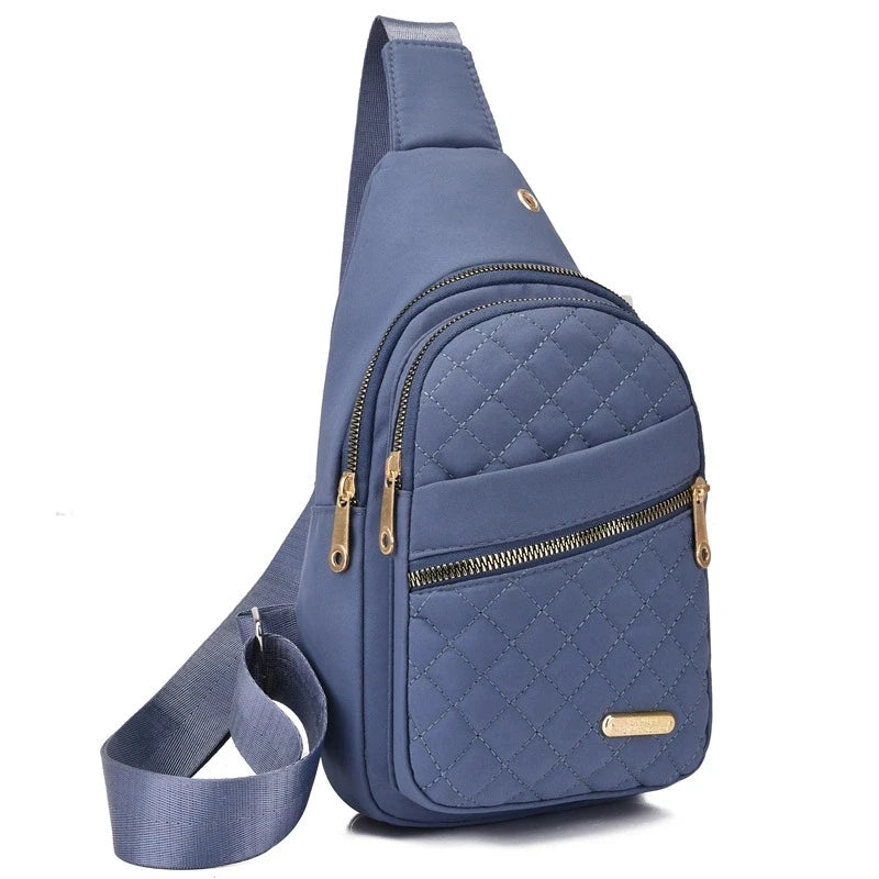 A navy blue quilted crossbody sling bag with gold-toned zippers and a matching strap.