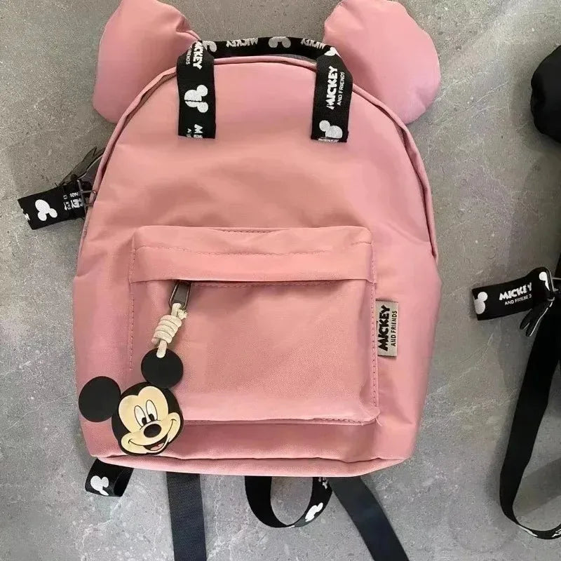A pink Mickey Mouse themed fashion backpack with a large front pocket and black straps.