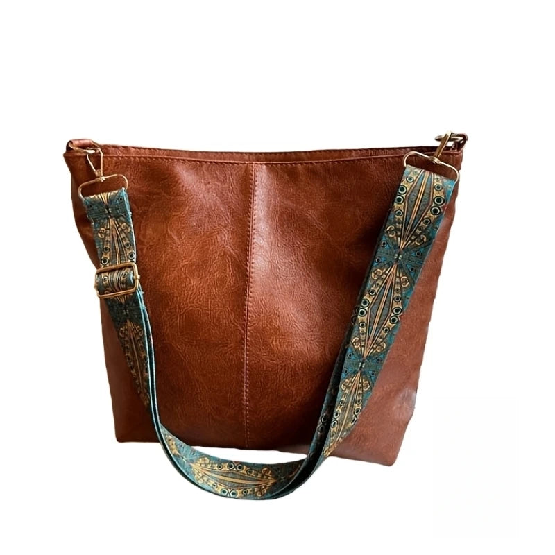 A brown leather geometric strap crossbody hobo bag with a teal patterned strap.
