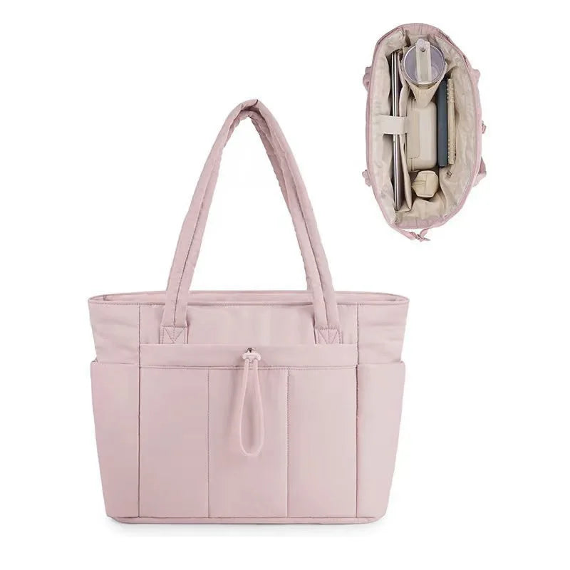A light pink quilted tote bag with a flap closure and interior pocket is shown against a white background.