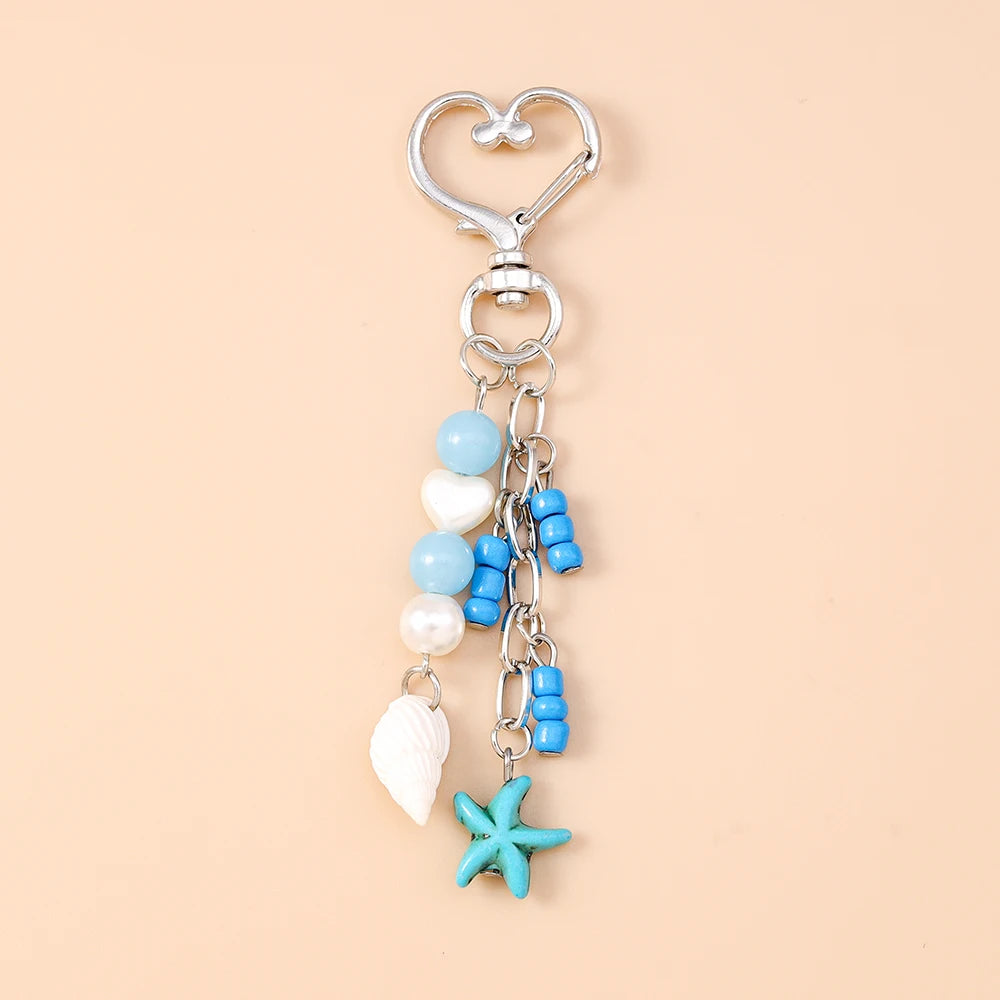Silver keychain featuring a starfish charm and various blue and white pearl-like beads.