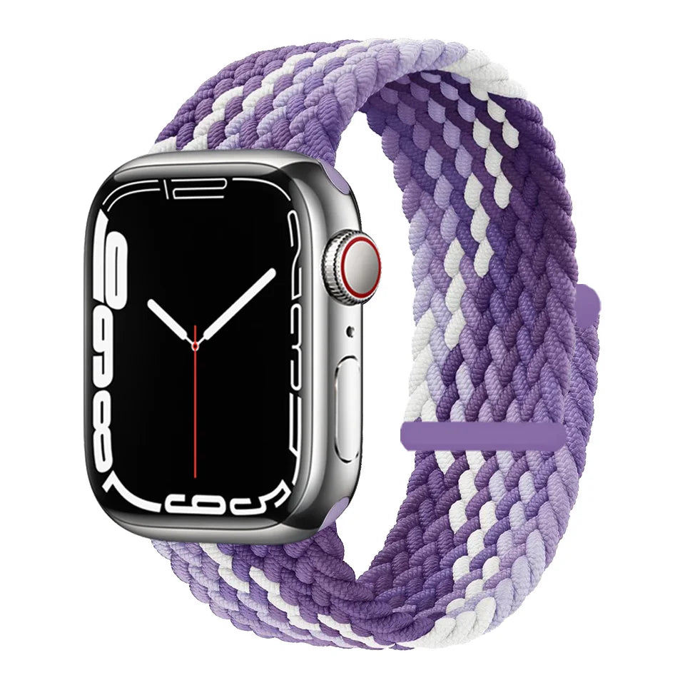 A silver Apple Watch is shown with a purple and white braided stretch band wrapped around it.
