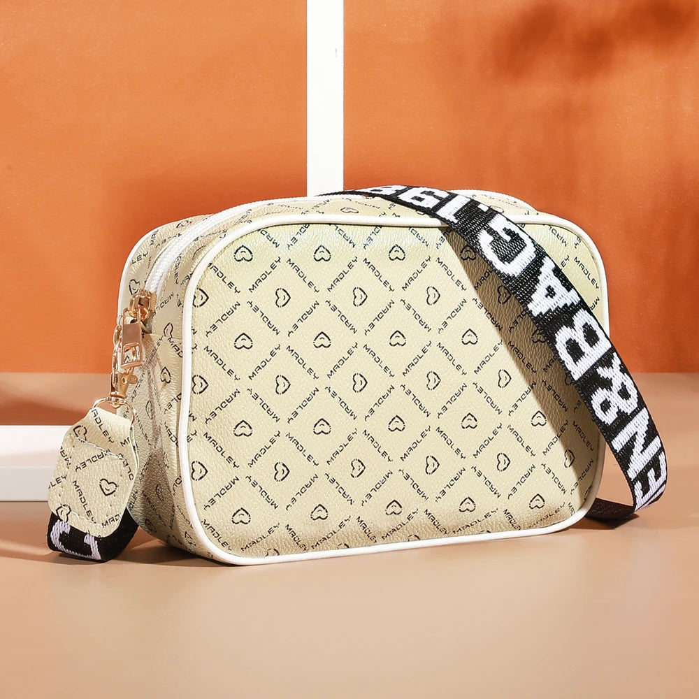 A beige and black patterned fashion crossbody shoulder bag resting on a smooth surface.