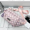 A pink plaid crossbody chest bag with a pink adjustable strap resting on a white surface.
