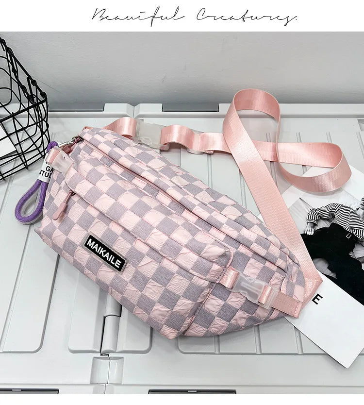 A pink plaid crossbody chest bag with a pink adjustable strap resting on a white surface.