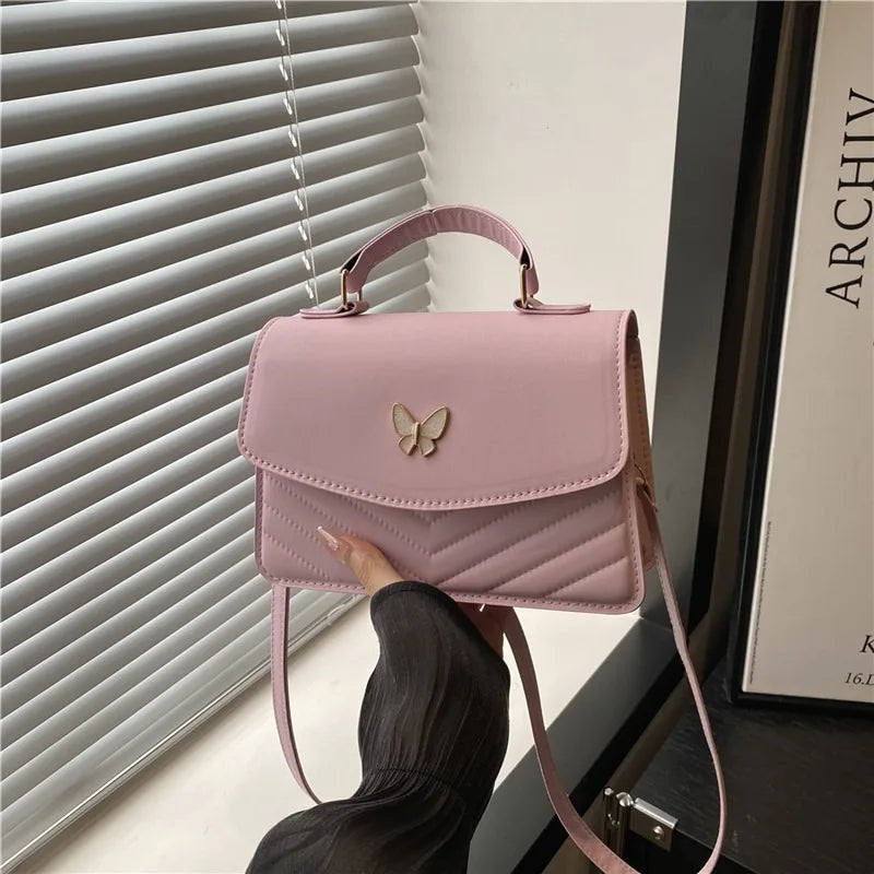 A pink textured shoulder messenger bag is shown against a window blind.