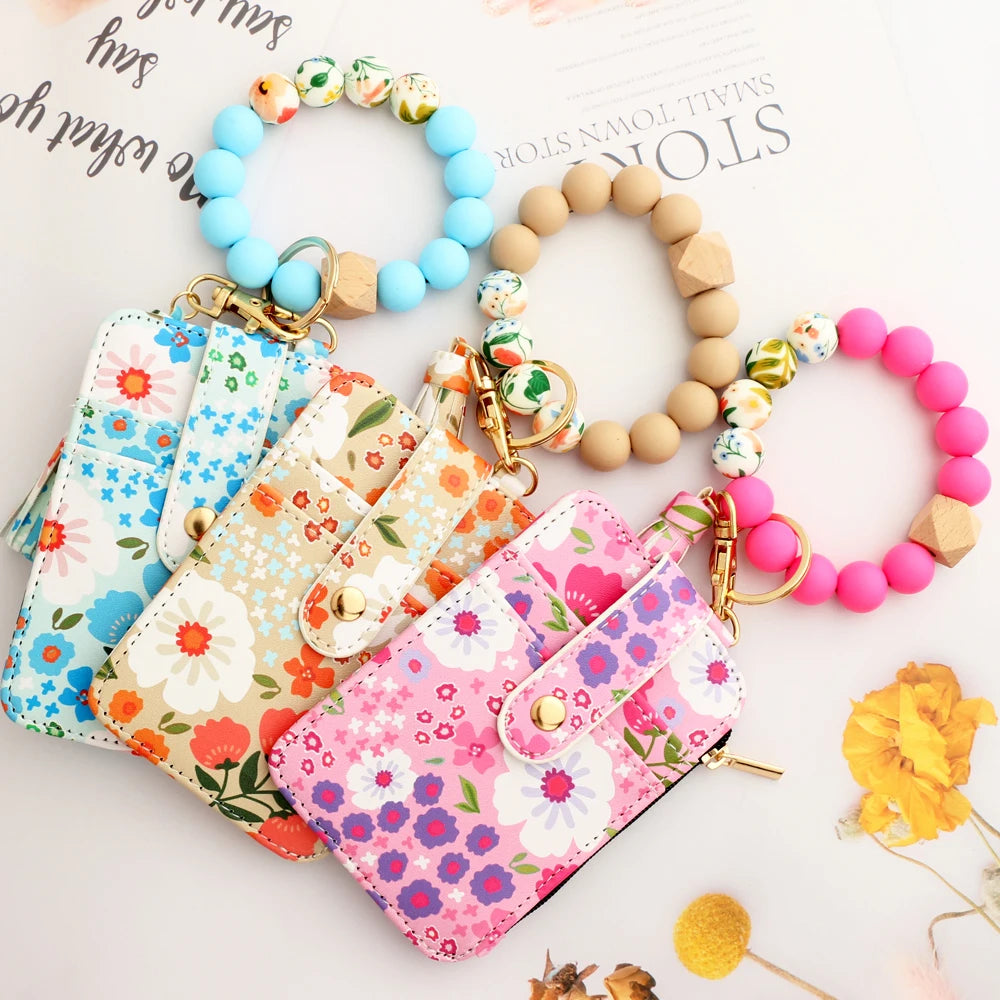 A collection of silicone bead and PU leather key chain wallets and bracelets displayed on a white background.