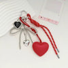 A red and silver bow key chain bag charm featuring a heart pendant and dangling chains.